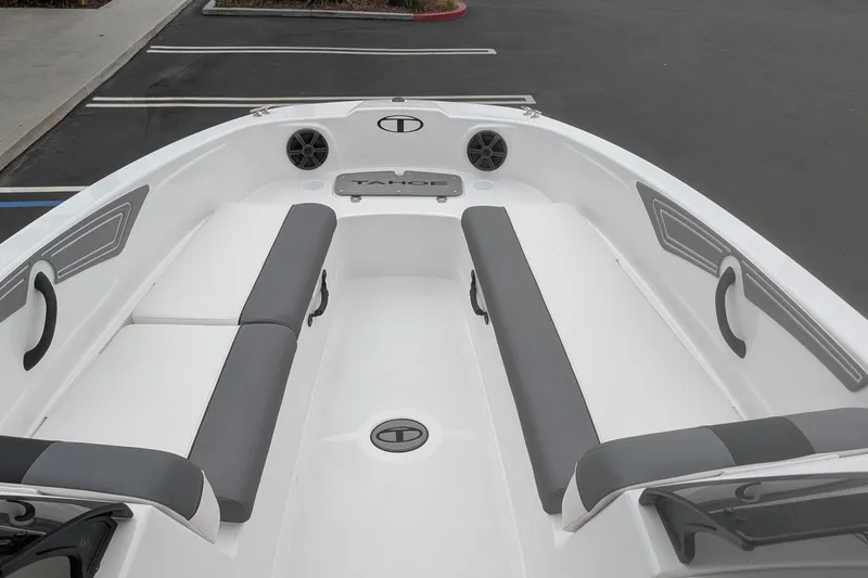 Slide: The Image of 2026 Tahoe T21 boat interior with gray and white seating, docked in a parking area. - 11