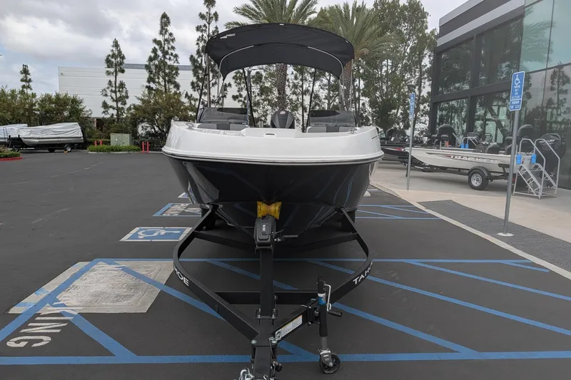 Slide: The Image of 2026 Tahoe T21 boat on trailer in parking lot, surrounded by trees and buildings. - 2
