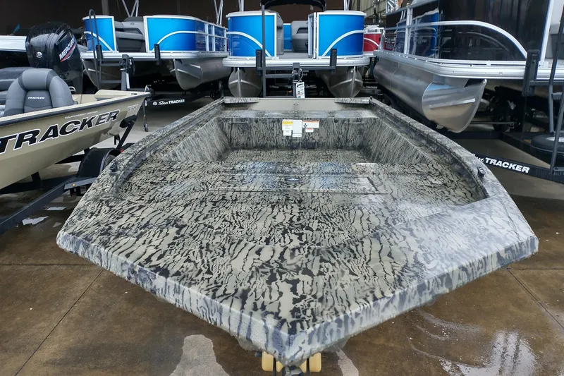 Slide: The Image of 2026 Tracker Grizzly 1648 Utility boat with camouflage design, displayed in a showroom. - 2