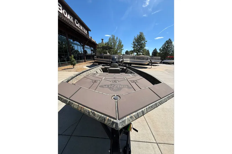 Slide: The Image of 2026 Tracker Grizzly 1860 CC boat displayed outside a boat center under a clear blue sky. - 13
