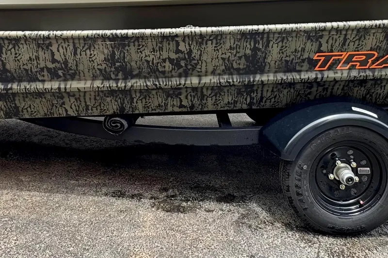 The Image of 2026 Tracker Grizzly 15 Jon boat with camouflage design and visible trailer wheel. - 0