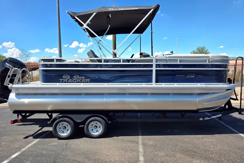 The Image of 2026 Sun Tracker SportFish 20 DLX pontoon boat on trailer, under clear blue sky. - 0