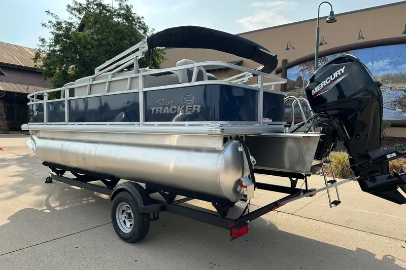 Slide: The Image of 2026 Sun Tracker Bass Buggy 18 DLX pontoon boat with Mercury outboard motor on trailer. - 2