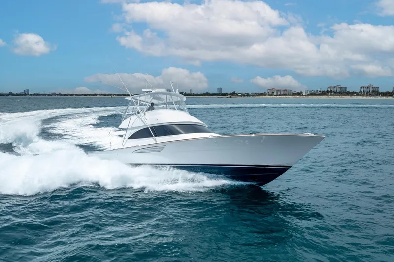 Slide: The Image of 2026 Viking 54 Convertible yacht cruising on open water under a partly cloudy sky. - 13