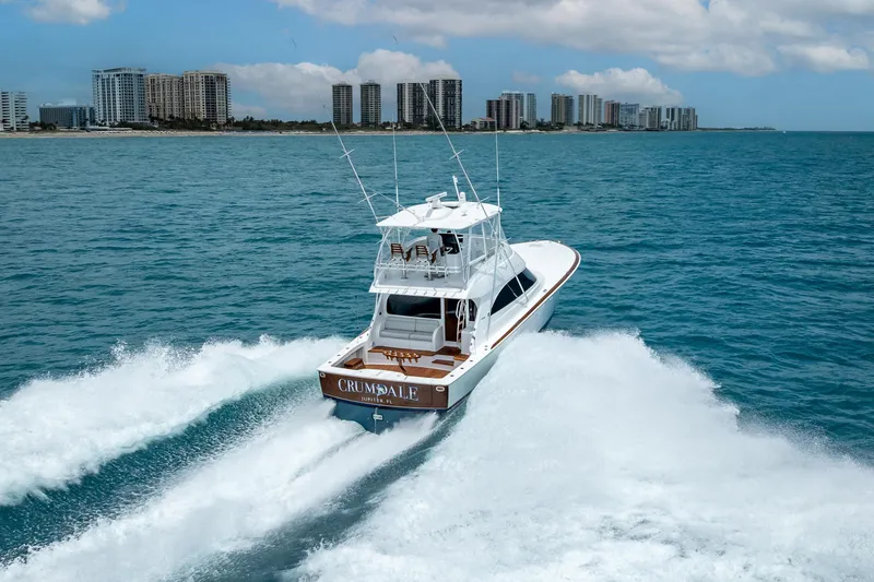 Slide: The Image of 2026 Viking 54 Convertible yacht cruising near a city skyline on a sunny day. - 19