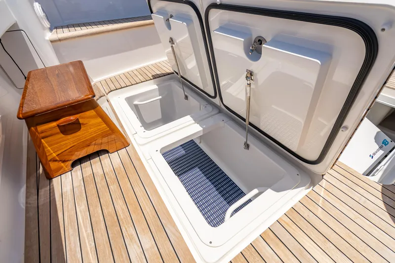 Slide: The Image of 2026 Viking 54 Convertible yacht deck with open storage compartments and wooden step. - 23