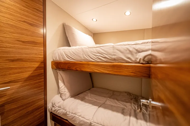 Slide: The Image of Interior of 2026 Viking 54 Convertible yacht with cozy bunk beds and wooden finish. - 46