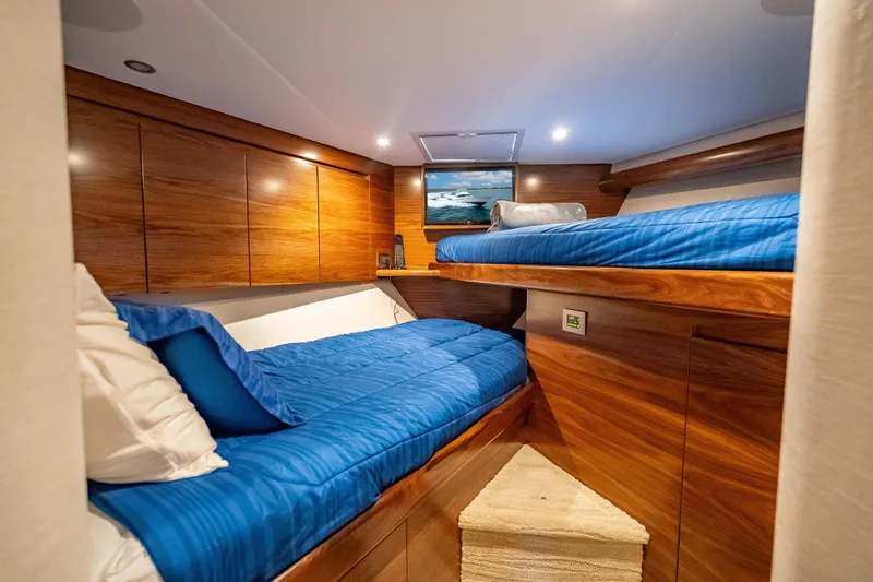 Slide: The Image of Luxurious cabin interior of 2026 Viking 54 Convertible yacht with wooden finish and blue bedding. - 47