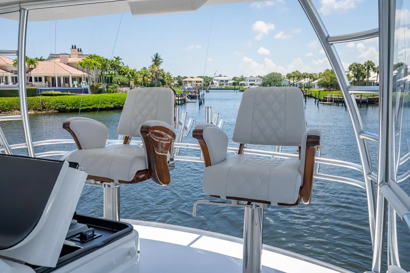 Slide: The Image of Luxury helm chairs on 2026 Viking 54 Convertible yacht, overlooking serene waterfront homes. - 69