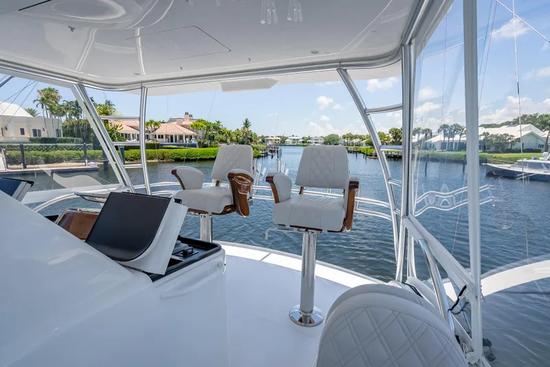 Slide: The Image of Flybridge view of 2026 Viking 54 Convertible yacht, featuring luxurious seating and scenic waterfront. - 70
