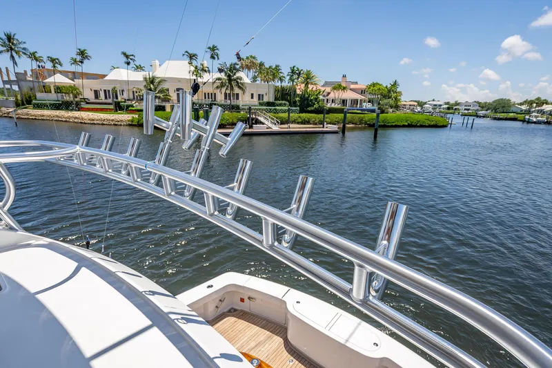 Slide: The Image of 2026 Viking 54 Convertible yacht with rod holders, docked near waterfront homes. - 72