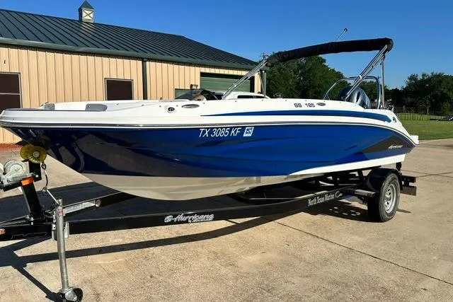 The Image of 2021 Hurricane SunDeck Sport 185 OB boat on trailer, blue and white design, parked outdoors. - 0