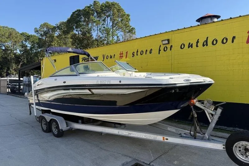 Slide: The Image of 2010 Monterey M5 Sport Boat on trailer, parked outside a yellow building. - 2