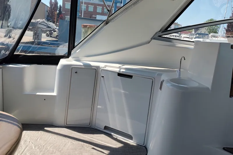 The Image of 1998 Cruisers Yachts 3870 Express interior with sleek white cabinetry and windows. - 14
