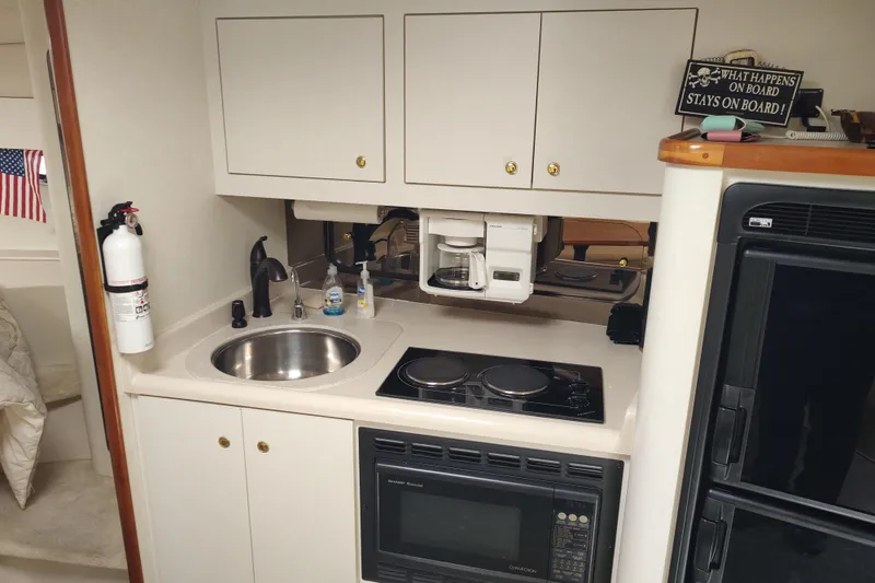 Slide: The Image of Compact kitchen in a 1998 Cruisers Yachts 3870 Express, featuring sink, stove, and microwave. - 23