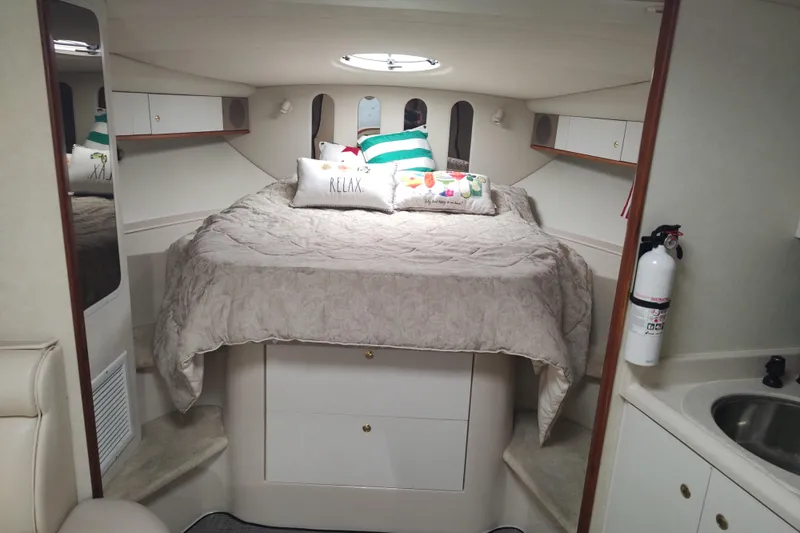 Slide: The Image of 1998 Cruisers Yachts 3870 Express cabin interior with bed, pillows, and fire extinguisher. - 24