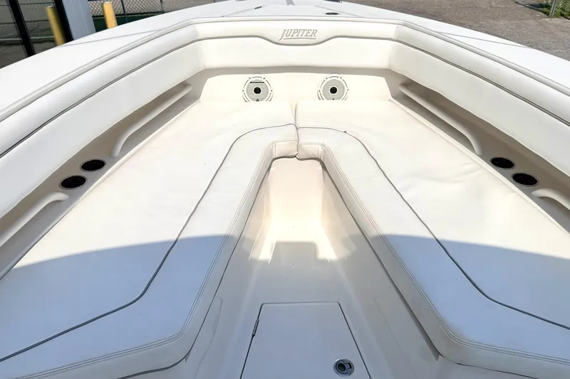 Slide: The Image of 2012 Jupiter 34 FS boat interior with white cushioned seating and cup holders. - 21