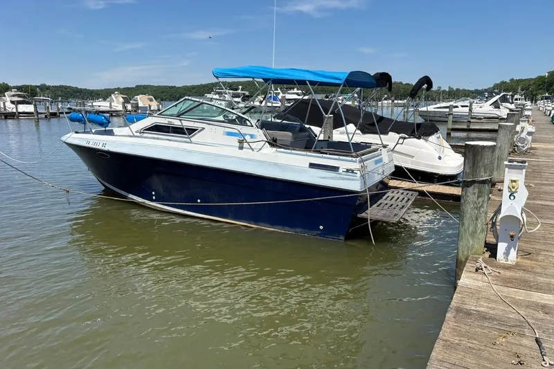 The Image of 1987 Four Winns 245 Vista boat docked at a marina on a sunny day. - 0