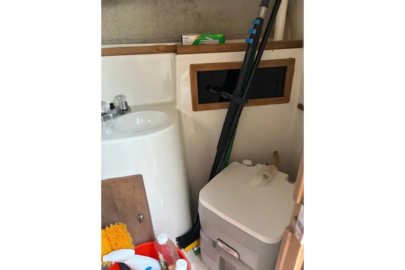Slide: The Image of 1987 Four Winns 245 Vista boat interior with sink, portable toilet, and cleaning supplies. - 4