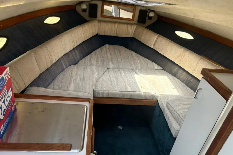 Slide: The Image of Interior cabin of 1987 Four Winns 245 Vista boat with cushioned seating and storage. - 8