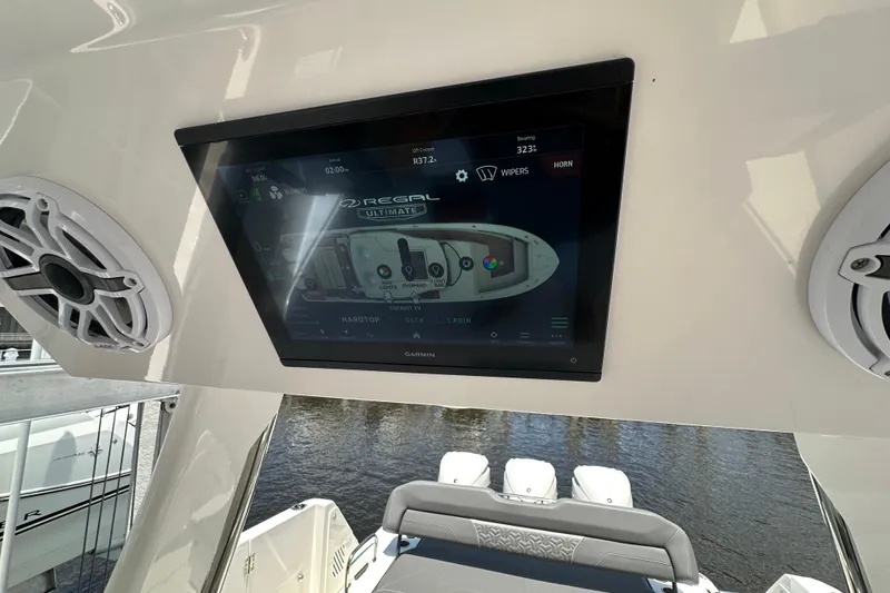 Slide: The Image of 2025 Regal 38 SAV boat dashboard with touchscreen display and speakers, overlooking water. - 15