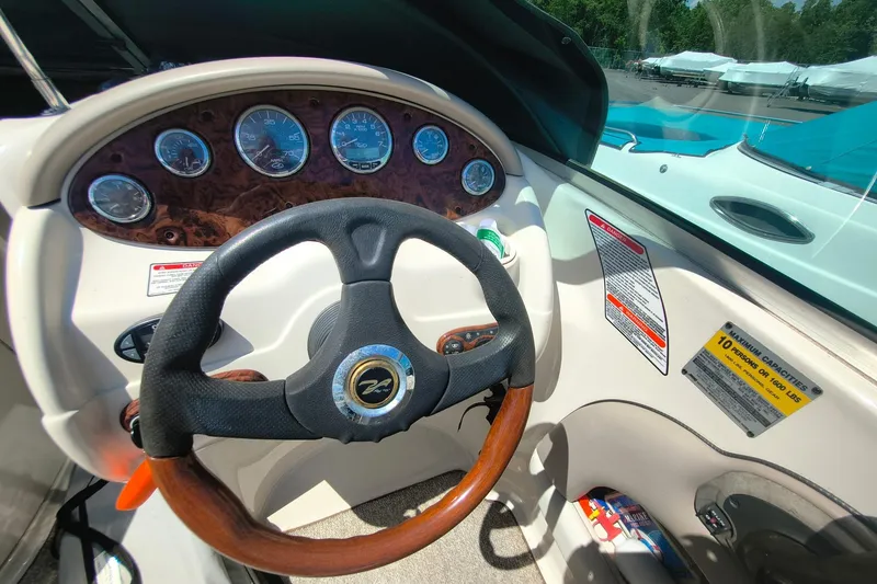 Slide: The Image of Steering wheel and dashboard of a 2004 Sun Deck 220 boat, featuring gauges and capacity label. - 1