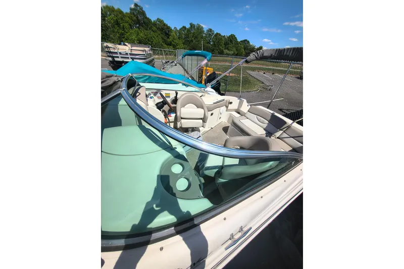 Slide: The Image of 2004 Sun Deck 220 boat interior with seating and steering, parked outdoors under blue sky. - 2