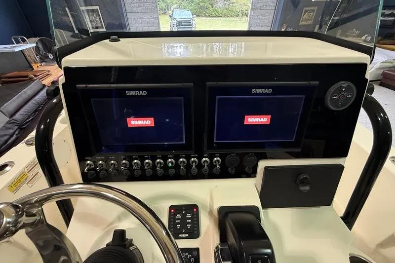 Slide: The Image of 2023 Sea Born FX22 Bay boat dashboard with dual Simrad displays and controls. - 12
