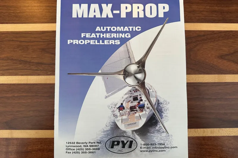 Slide: The Image of Max-Prop automatic feathering propellers brochure on wooden table, featuring a sailing yacht. - 157