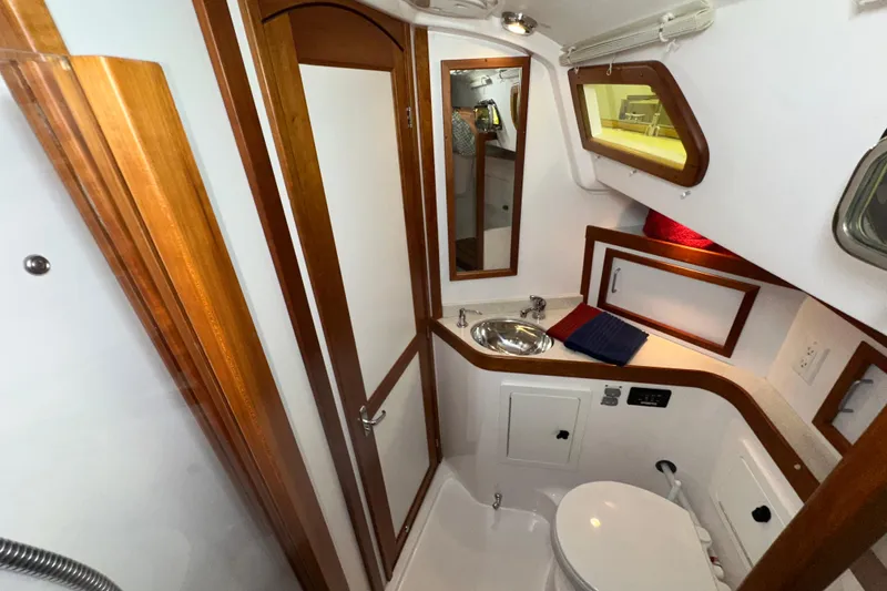 Slide: The Image of 2007 Sabre 386 yacht bathroom with wooden accents, sink, mirror, and porthole window. - 41