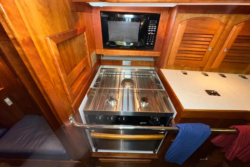 Slide: The Image of 2007 Sabre 386 yacht kitchen with stove, microwave, and wooden cabinetry. - 59