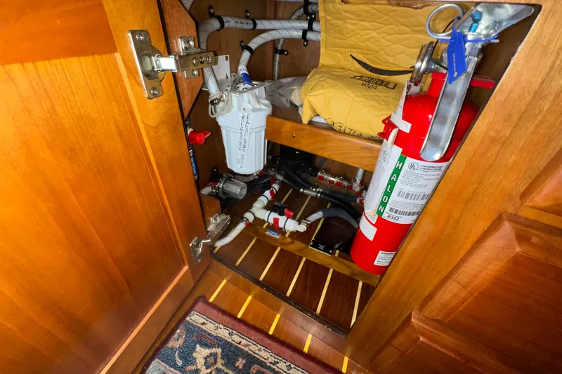 Slide: The Image of Wooden cabinet interior with fire extinguisher and plumbing components on a 2007 Sabre 386. - 61
