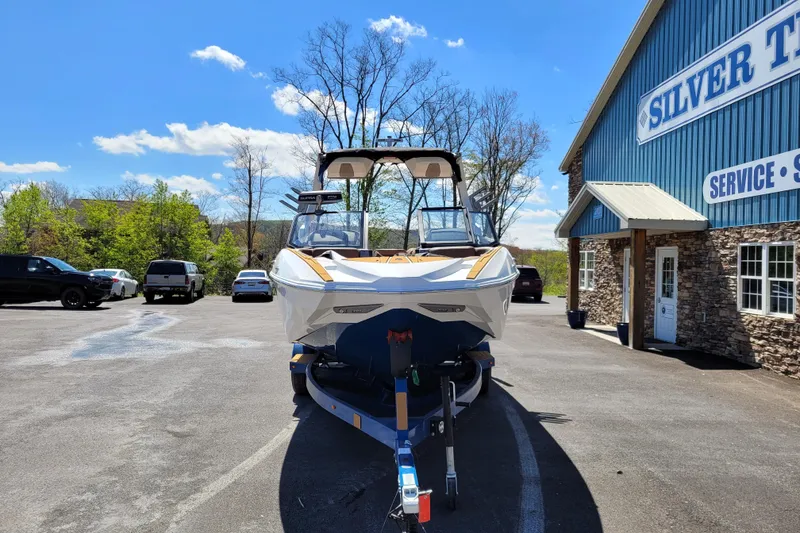 Slide: The Image of 2026 Supra SV 400 boat on trailer outside Silver building under blue sky. - 3