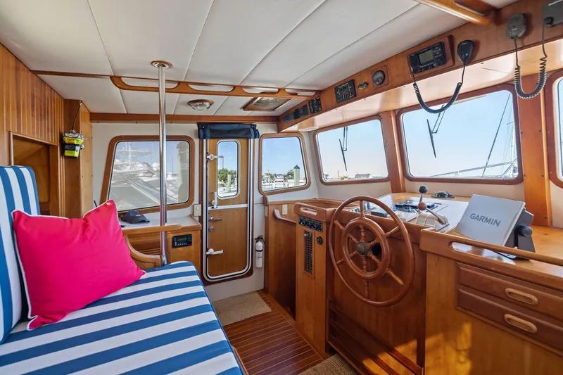Slide: The Image of 1999 Kadey-Krogen 39 yacht interior with wooden helm, striped seating, and navigation equipment. - 13