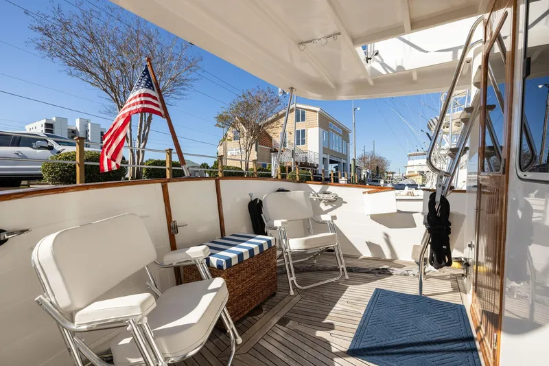 Slide: The Image of 1999 Kadey-Krogen 39 yacht deck with seating, American flag, and marina view. - 36