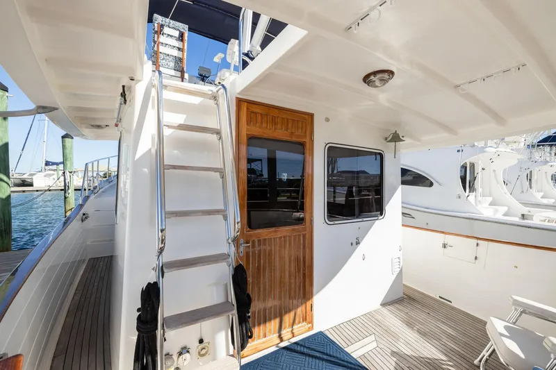 Slide: The Image of 1999 Kadey-Krogen 39 yacht deck with wooden door and ladder, docked at marina. - 38