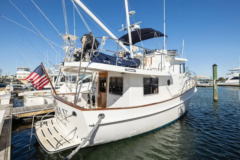 Slide: The Image of 1999 Kadey-Krogen 39 yacht docked, featuring American flag and spacious deck. - 49