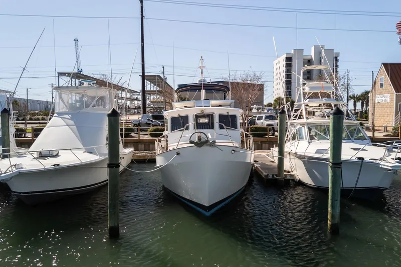 Slide: The Image of 1999 Kadey-Krogen 39 yacht docked between two boats in a marina. - 50