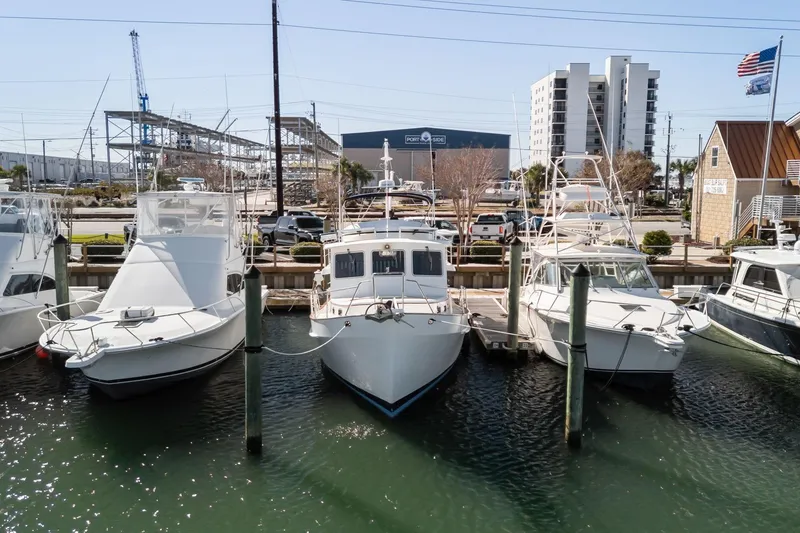 Slide: The Image of Docked boats including a 1999 Kadey-Krogen 39 at a marina with buildings in the background. - 51