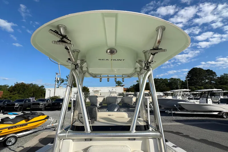 Slide: The Image of 2016 Sea Hunt Ultra 211 boat with T-top, parked in a marina under a blue sky. - 11