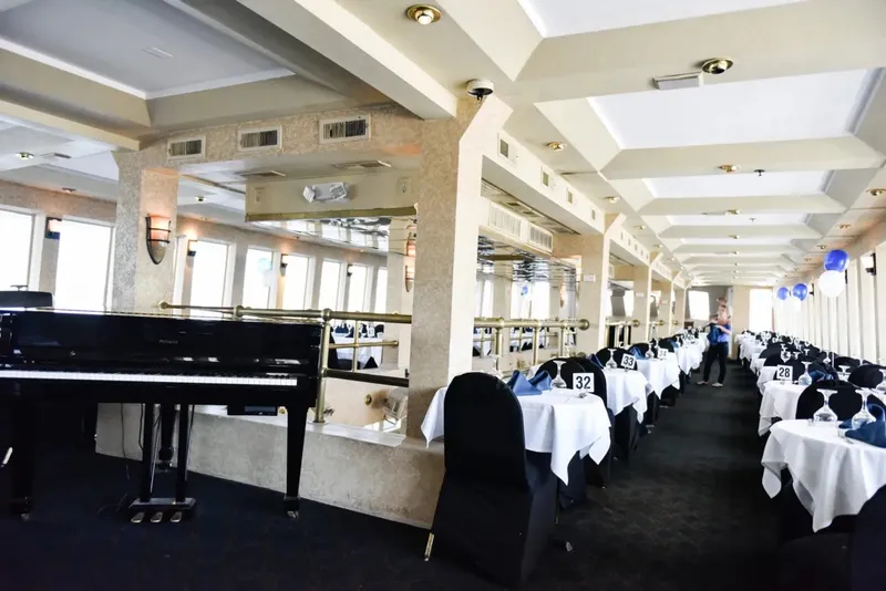 Slide: The Image of Elegant dining area on Blount 130 Dinner Cruise, featuring a grand piano and decorated tables. - 22