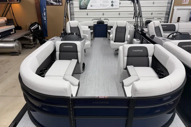 Slide: The Image of 2026 Harris Cruiser 210 CWDH pontoon boat with luxurious seating in showroom. - 2