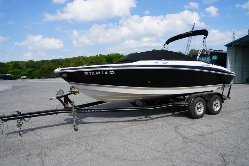 The Image of 2007 Four Winns 210 Horizon boat on trailer, parked outdoors under a blue sky. - 1
