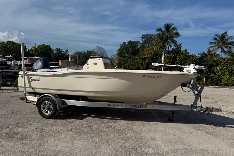 The Image of 2020 Scout 195 Sportfish boat on trailer, parked outdoors with palm trees in background. - 0