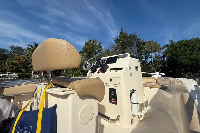 Slide: The Image of 2020 Scout 195 Sportfish boat interior with steering console and seating under clear blue sky. - 5