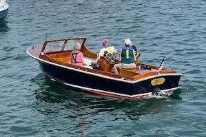 Slide: The Image of 1966 C Ray Hunt Surf Hunter boat with passengers cruising on the water. - 2