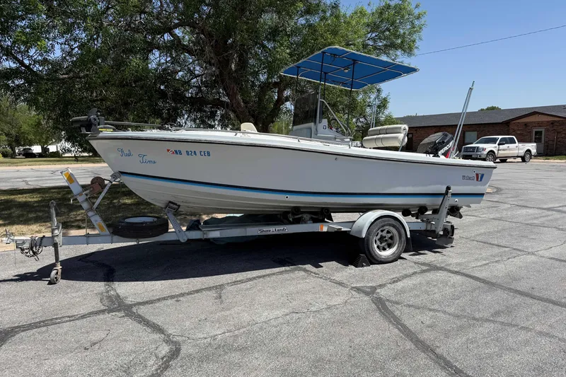 The Image of 1985 Wellcraft 180 Fisherman boat on trailer, parked outdoors under a tree. - 1