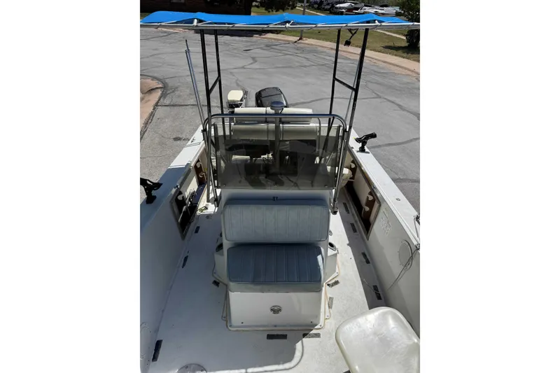 Slide: The Image of 1985 Wellcraft 180 Fisherman boat with blue canopy and seating, parked on pavement. - 3