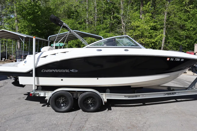 The Image of 2009 Chaparral Sunesta 244 boat on trailer, black and white design, parked outdoors. - 0