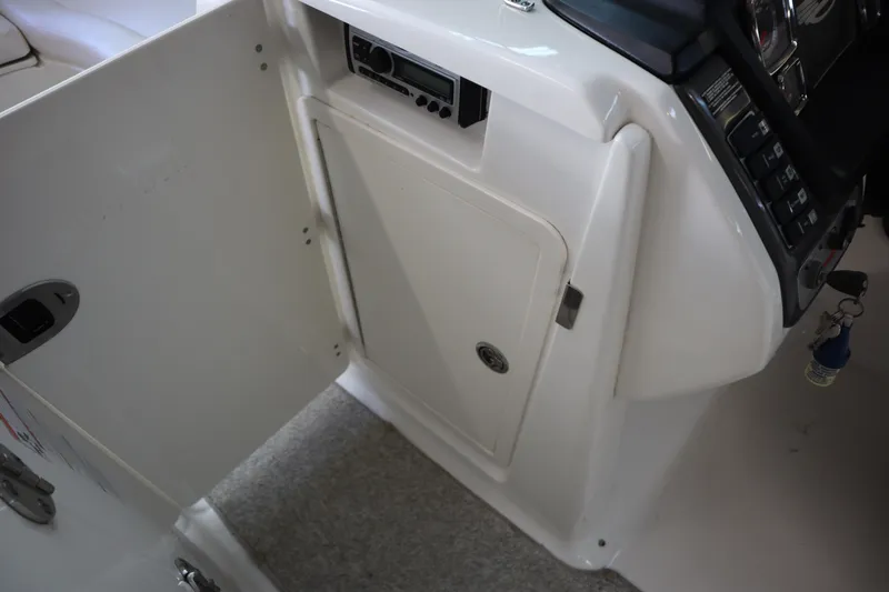 Slide: The Image of 2009 Chaparral Sunesta 244 boat interior storage compartment with open door and control panel. - 14